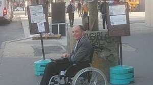 Afbeelding man in rolstoel bij bushalte in Frankrijk