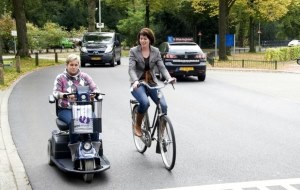 afbeelding vrouw op scootmobiel en vrouw op fiets