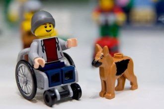 lego poppetje in rolstoel met hulphond